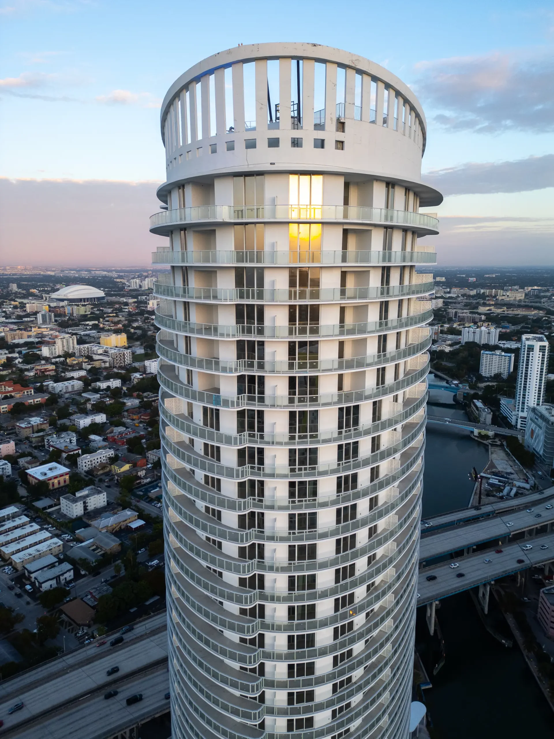 Aerial drone view of a round white high-rise tower at dusk near the Miami River, by Drone Permission