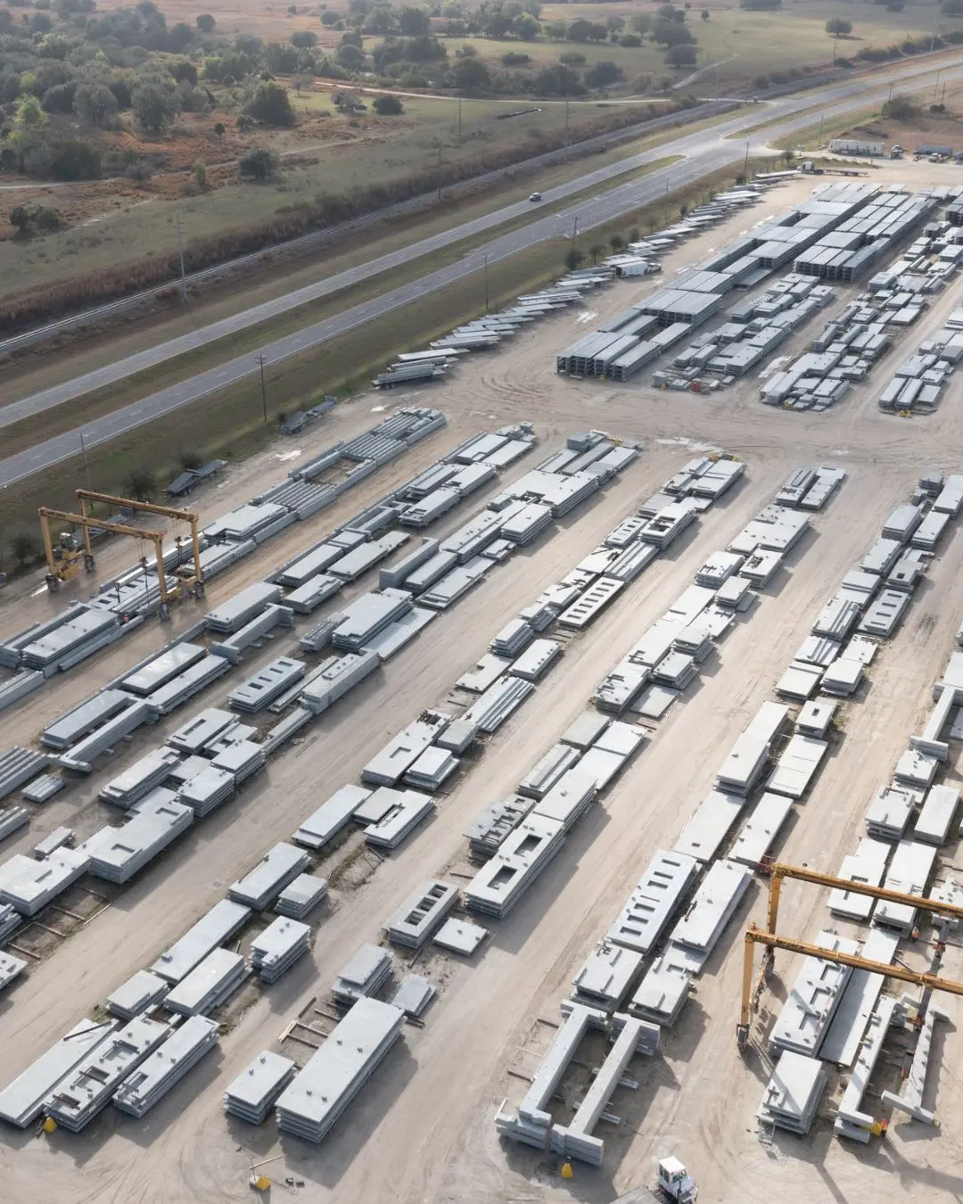 Aerial survey of an industrial yard with rows of modular buildings beside a highway