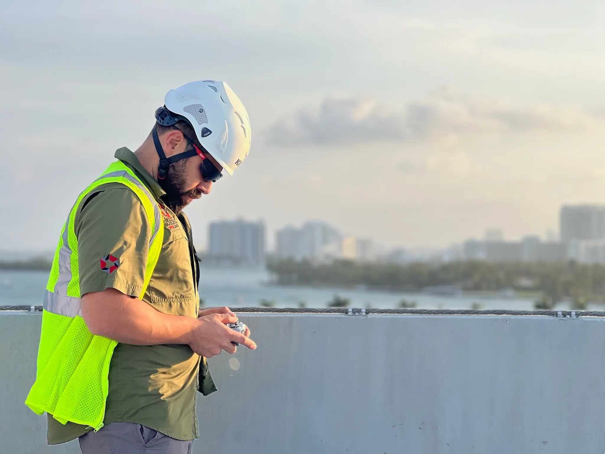 FAA Part 107 licensed drone pilot in hard hat and high visibility vest launching from roof level over the Florida coast, [CITY], by Drone Permission