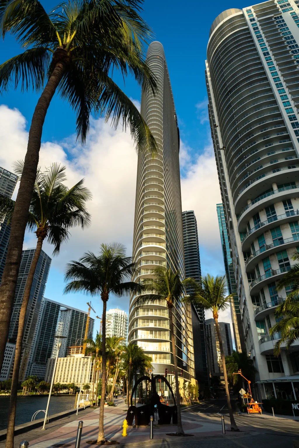 Street-level view of the Aston Martin Residences tower rising above palm trees in downtown Miami