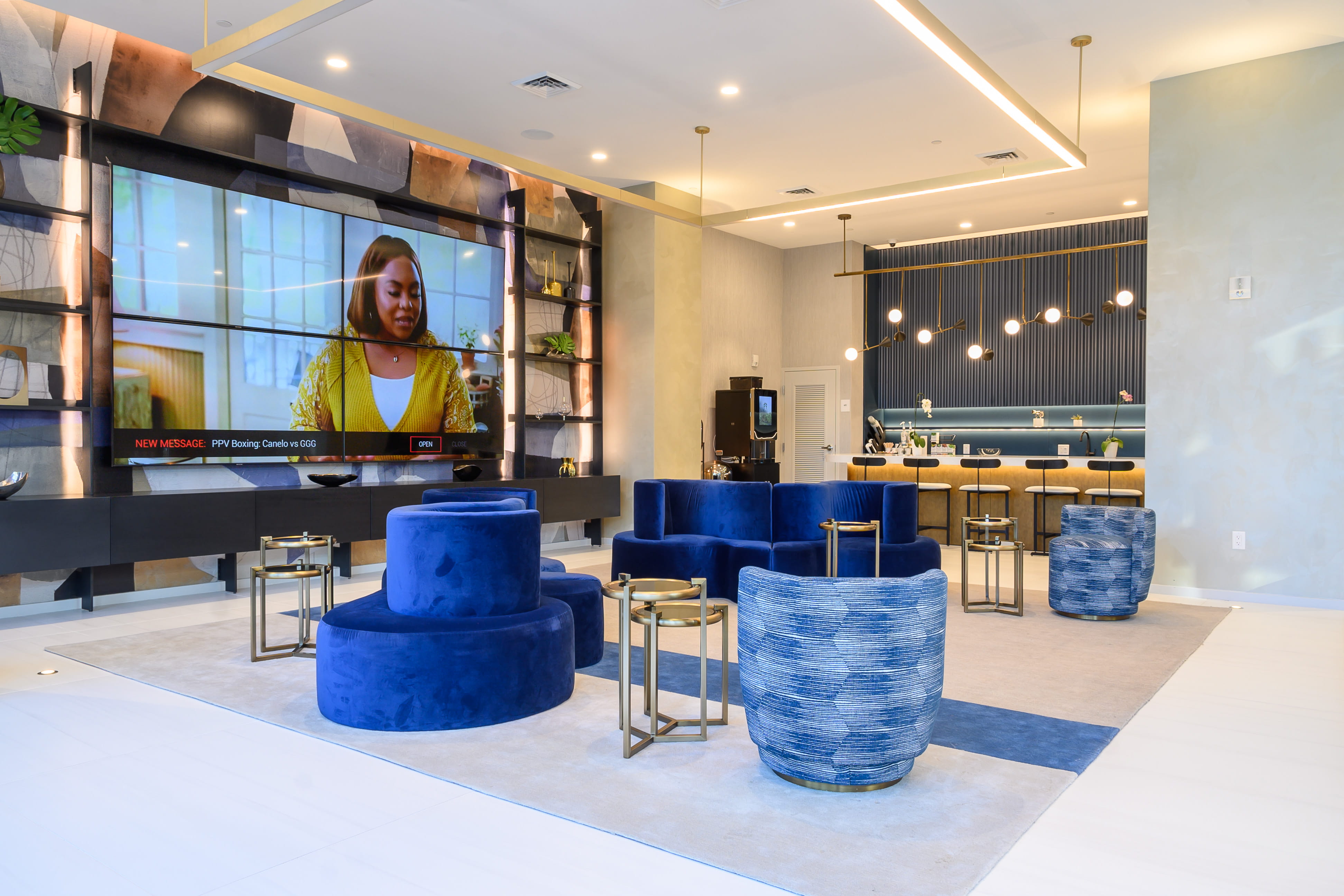 Graded interior frame of a resident lounge with blue velvet seating, a media wall and a coffee bar
