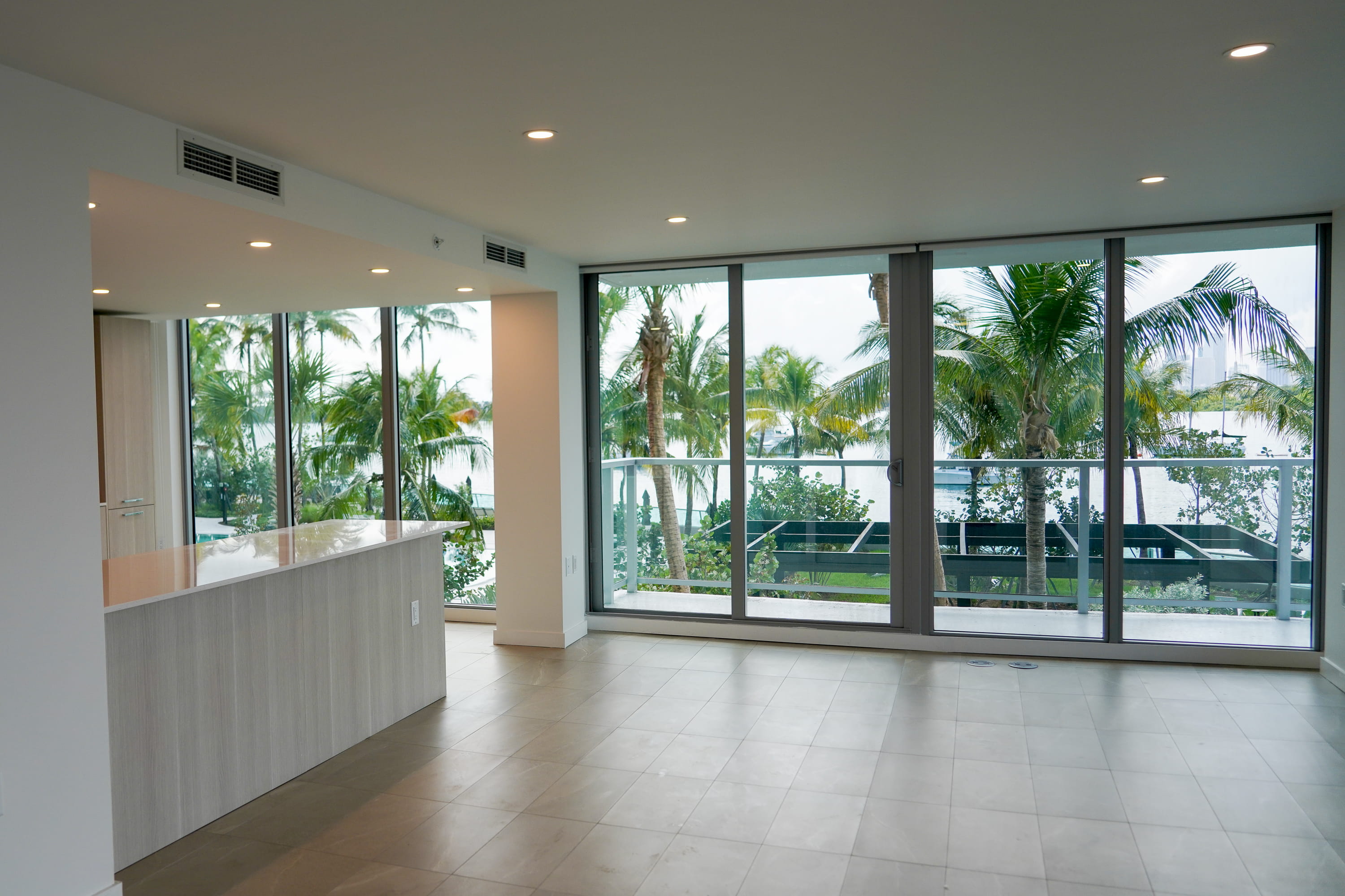 Modern waterfront condo interior with floor-to-ceiling windows overlooking palm trees at Flamingo Point in Miami Beach