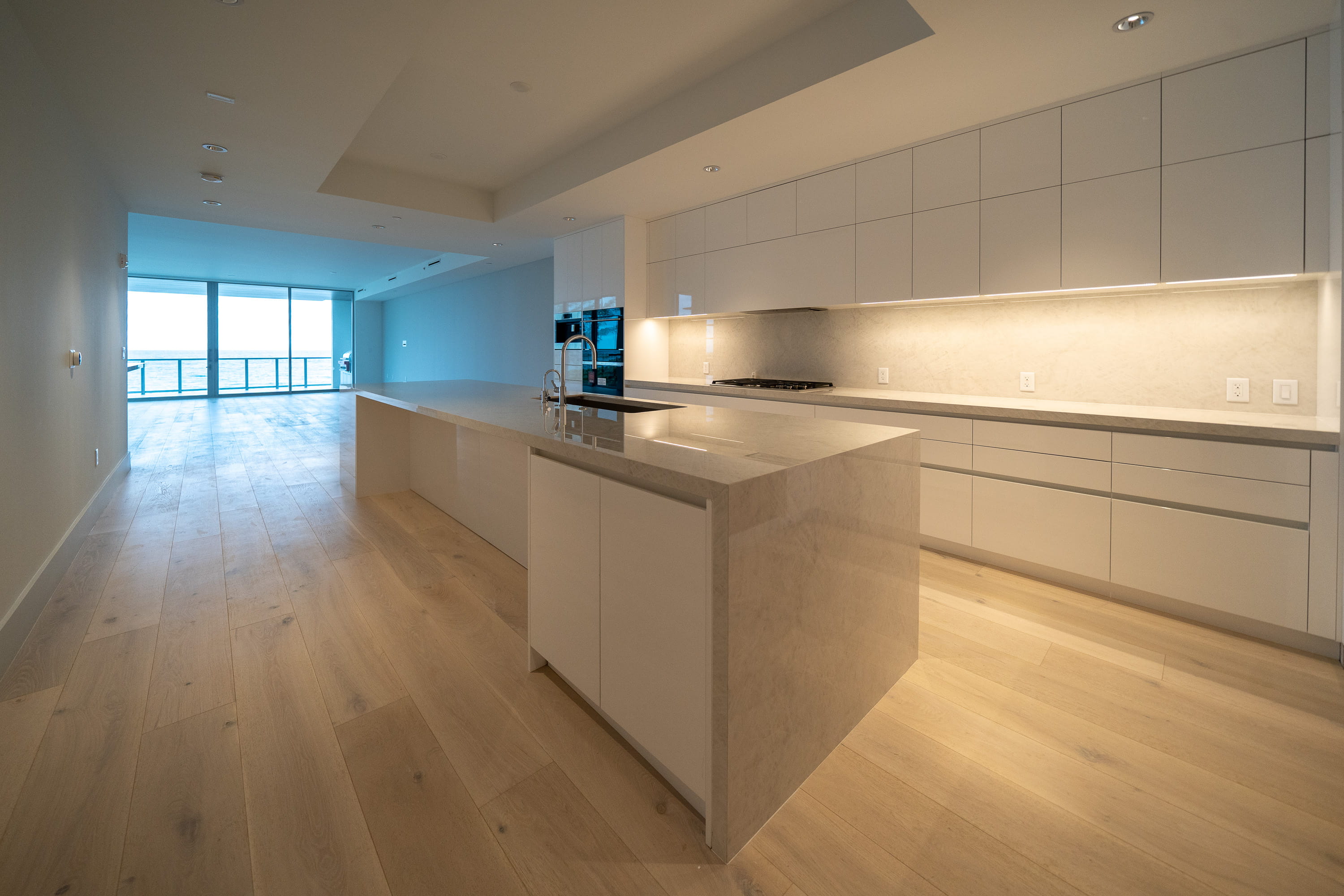 Modern white kitchen with a stone waterfall island and ocean views in a Delray Beach luxury condo