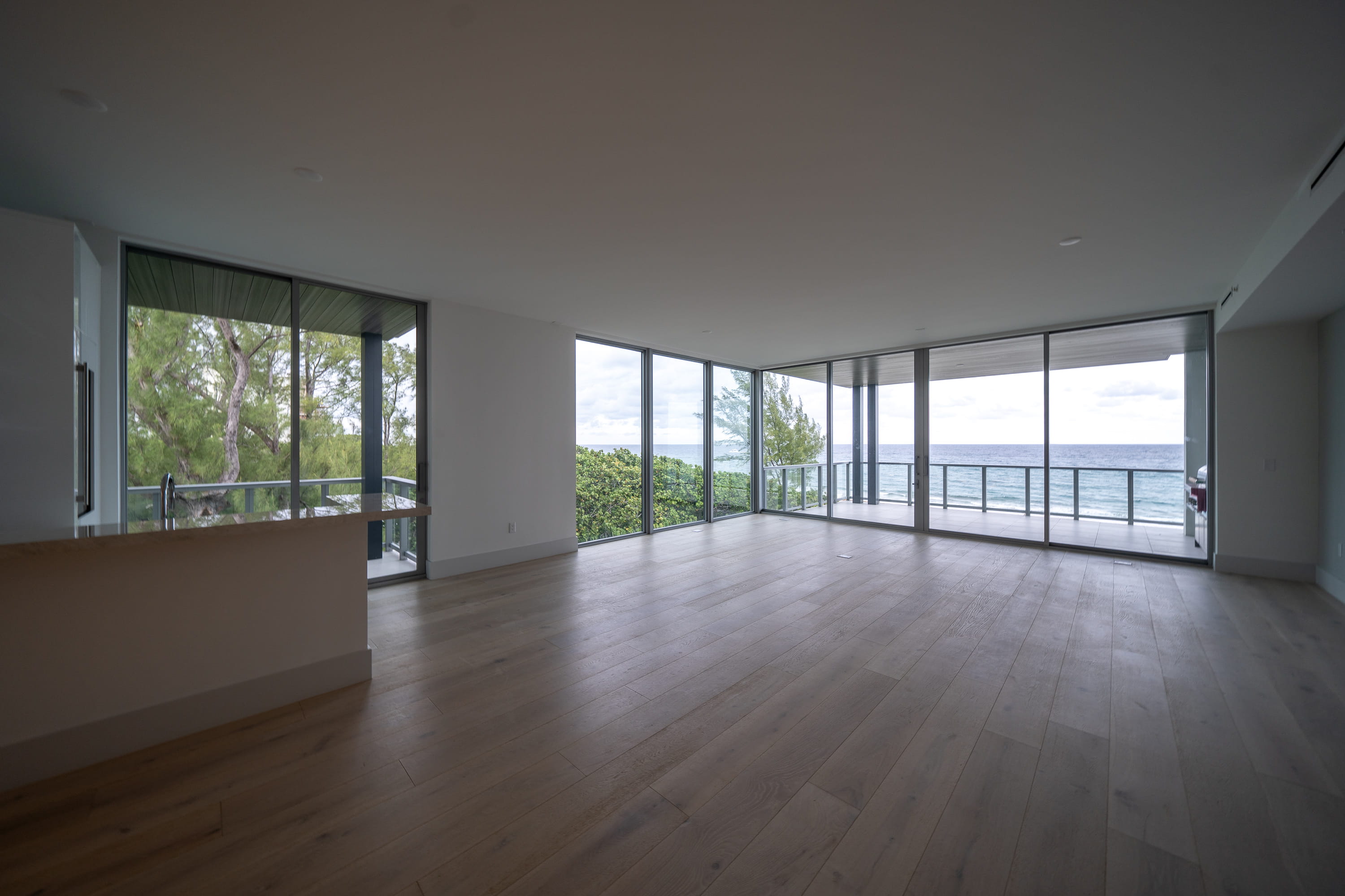 Empty oceanfront luxury condo interior with floor-to-ceiling windows and wraparound terrace in Delray Beach, Florida