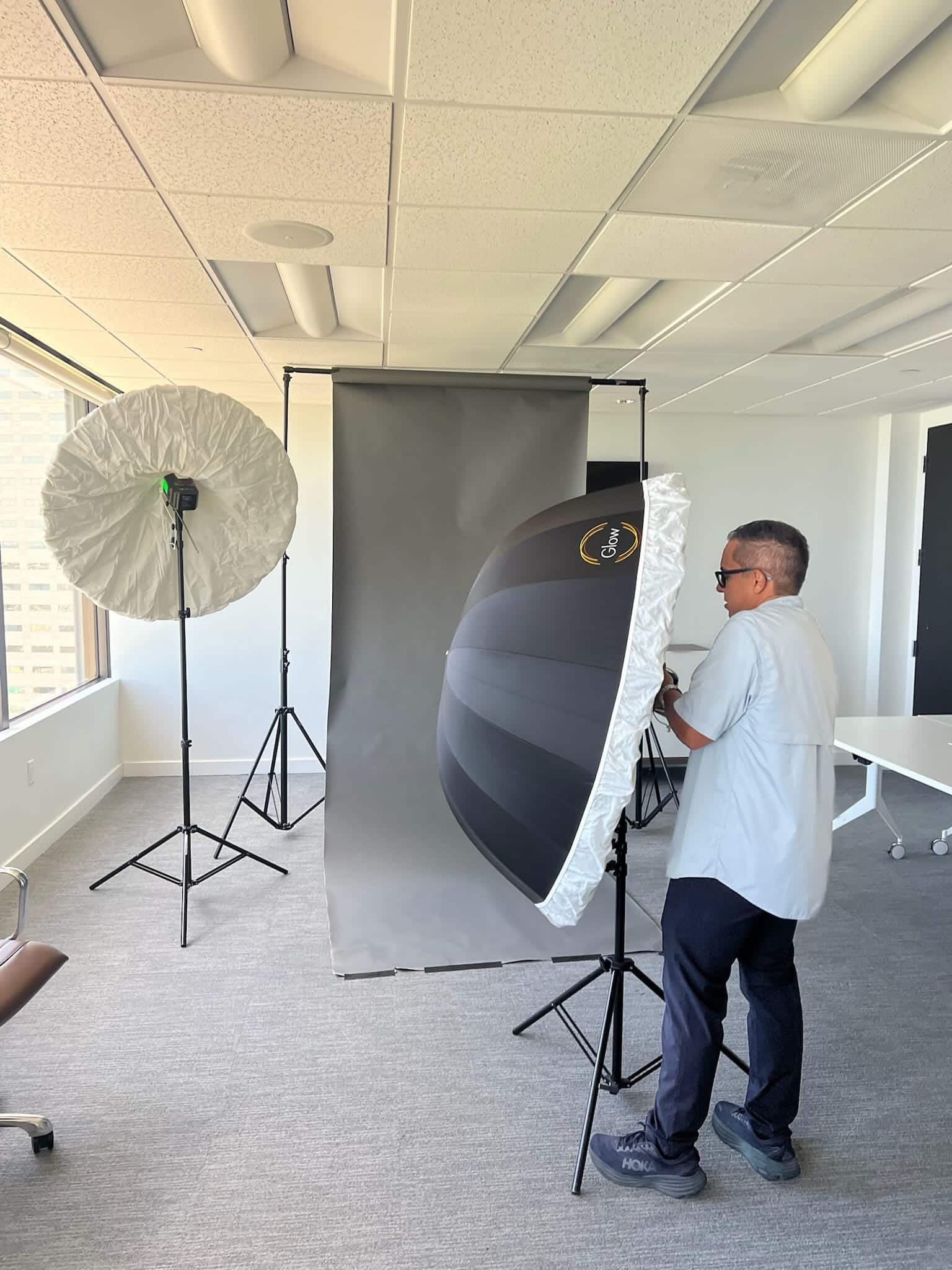 Drone Permission photographer setting up studio lighting and a gray backdrop for corporate headshots in a Florida office conference room