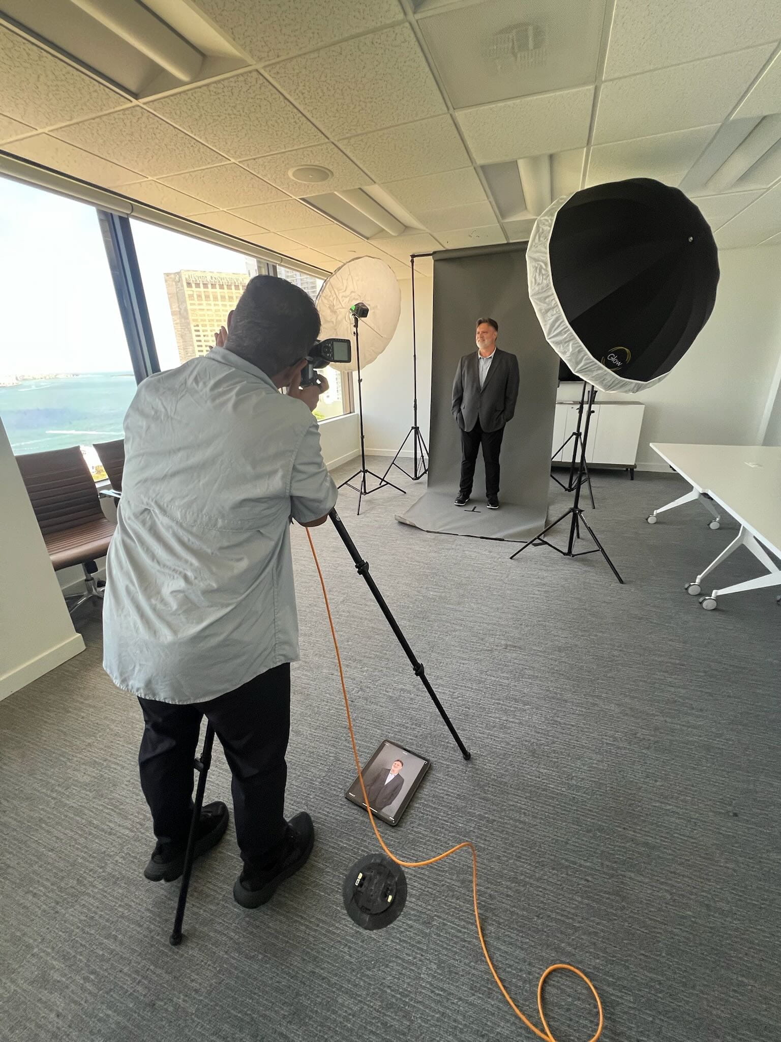Photographer shooting corporate headshots of a businessman in a high-rise office studio with waterfront views in Miami