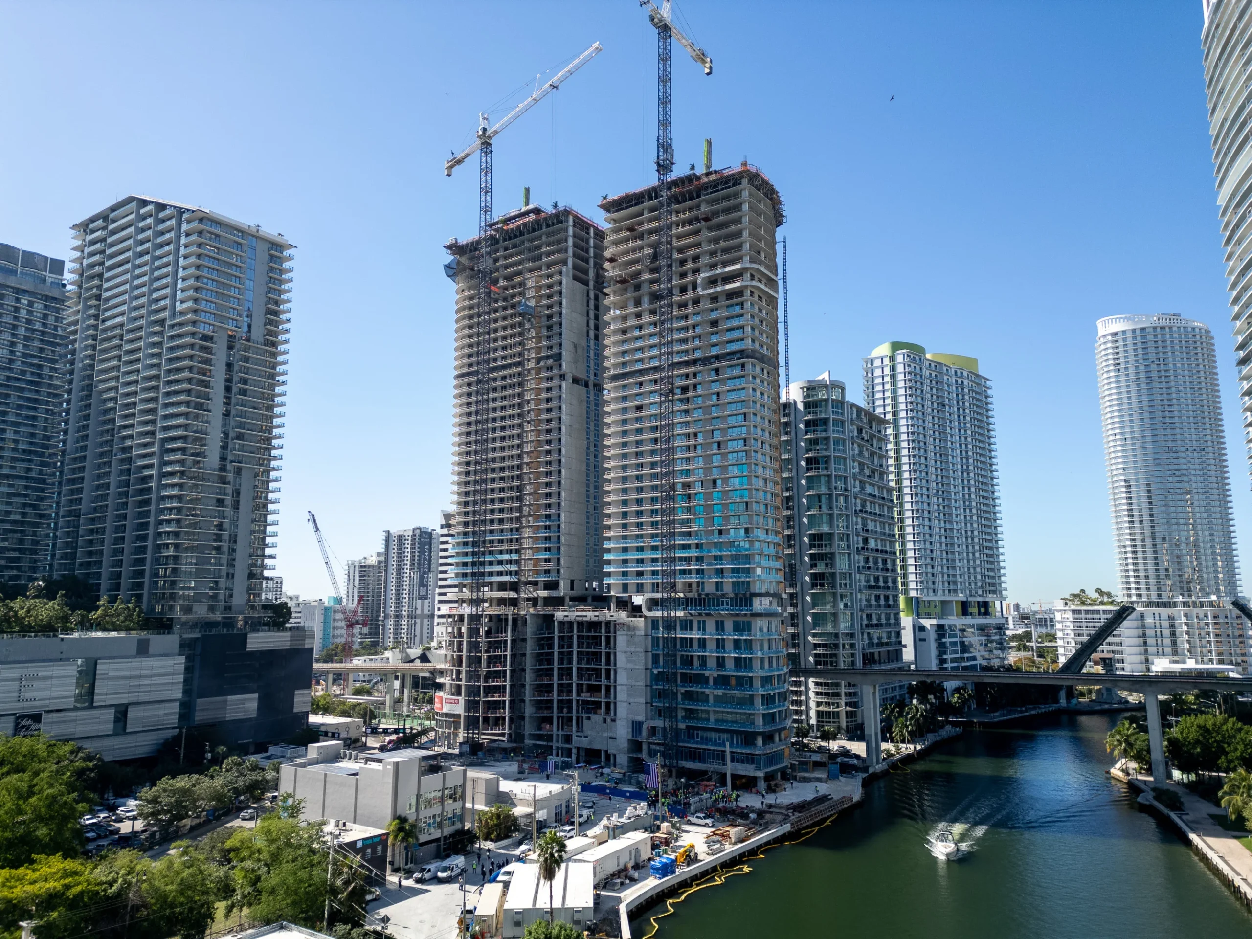 Aerial view of The Standard Residences and Lofty Brickell towers with tower cranes above the Miami River and Brickell skyline