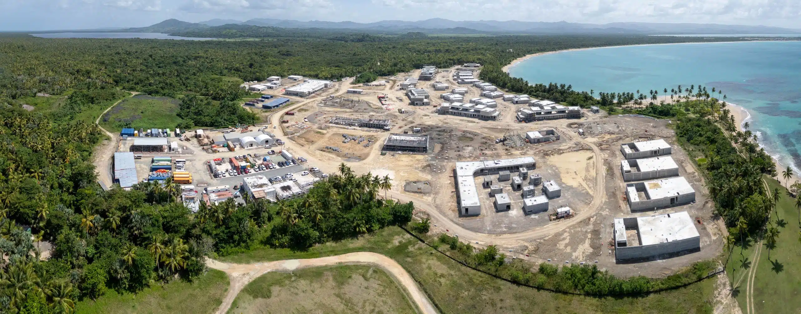 Panoramic aerial view of the Tropicalia beachfront resort construction site in September 2025, showing early-stage structures, cleared roads and staging areas along the coastline