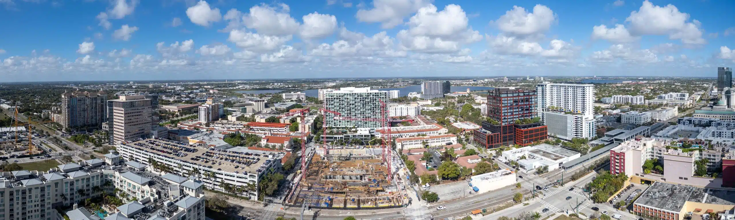Aerial panorama of downtown West Palm Beach with tower cranes over the WPB15CP project's excavation and foundation works at street level