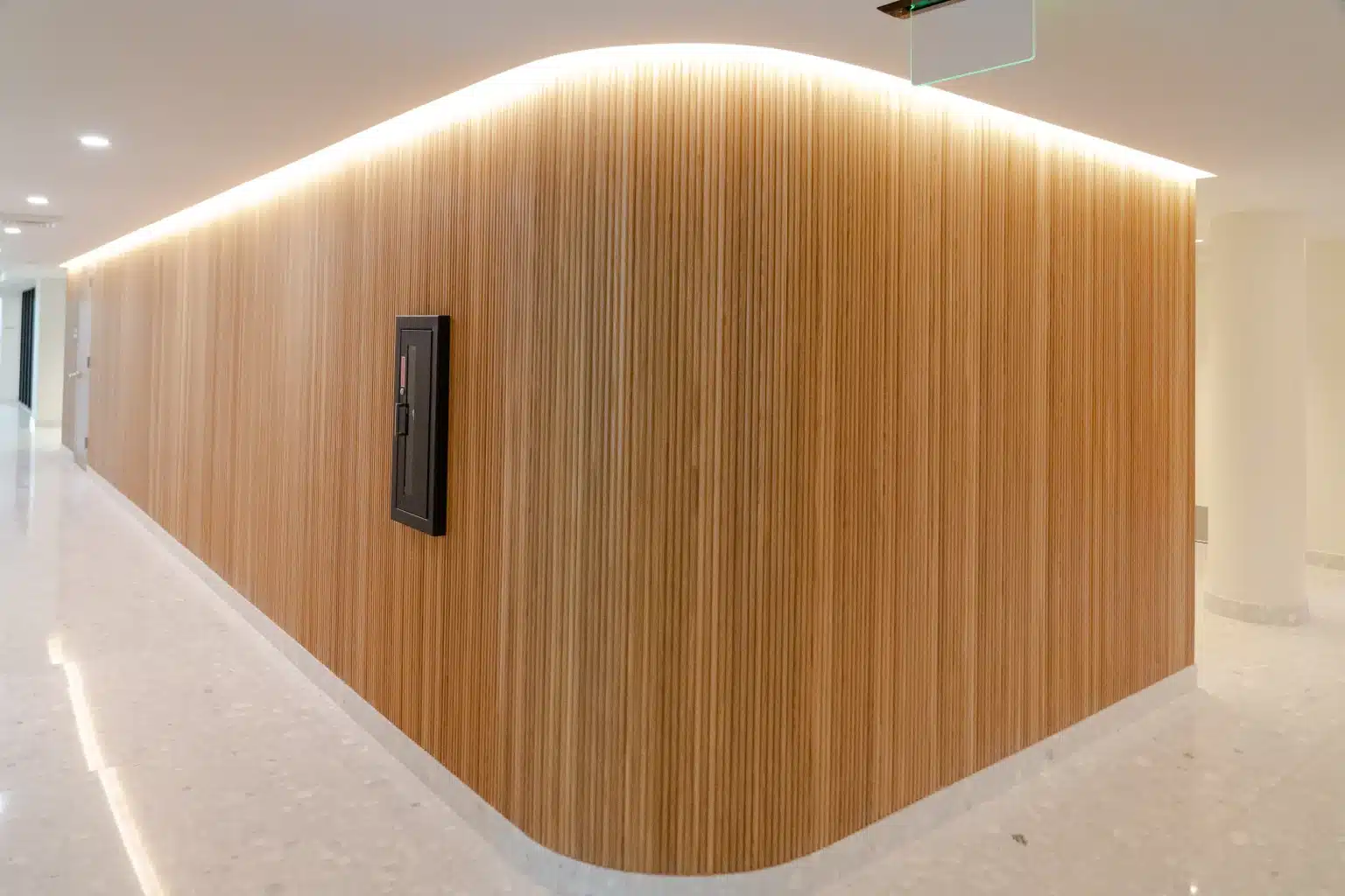 Curved wall of vertical wood slats with a backlit cove at Flamingo Point in Miami Beach