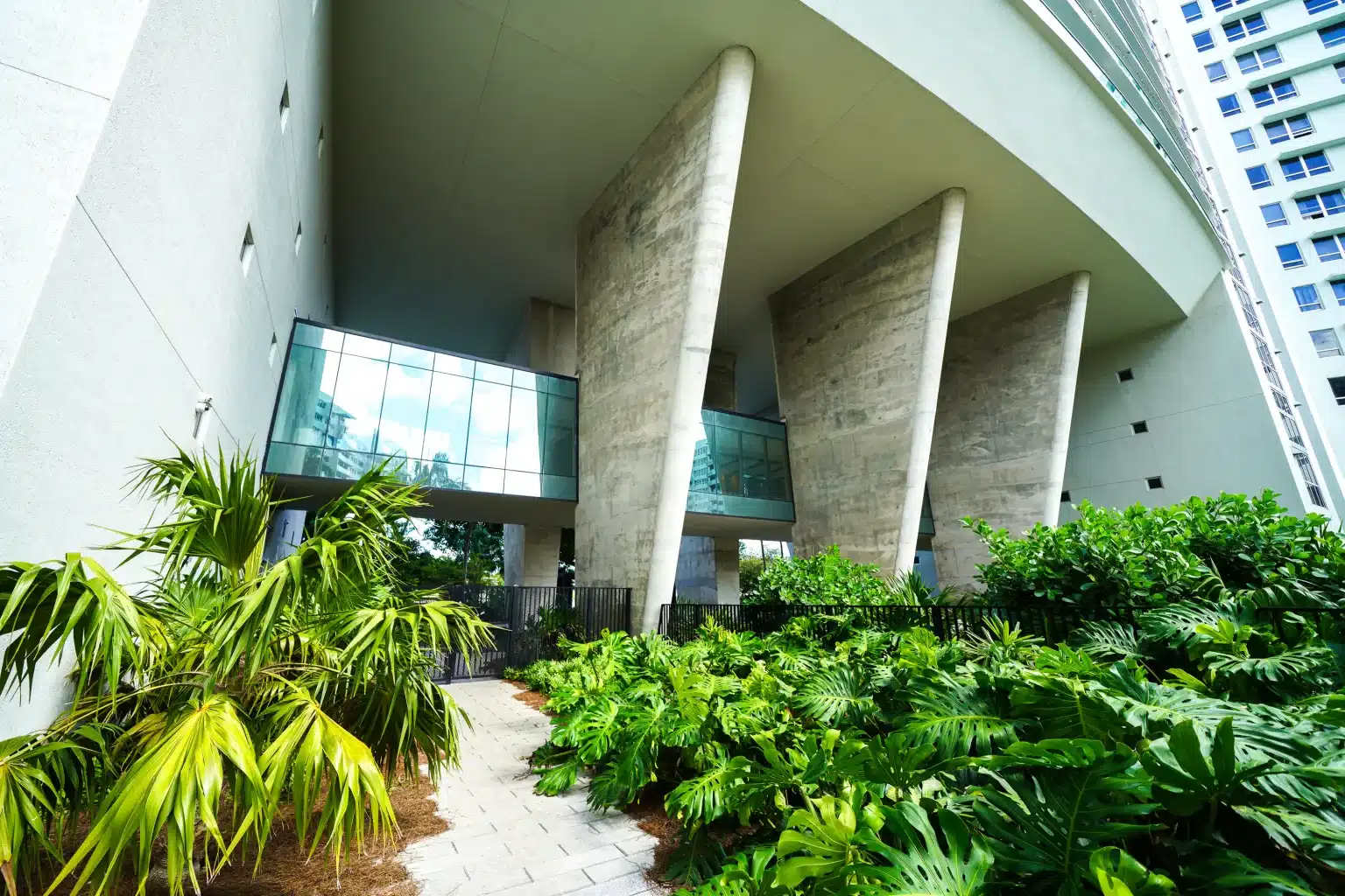 Angled board-formed concrete columns rising over a tropical garden at Flamingo Point in Miami Beach