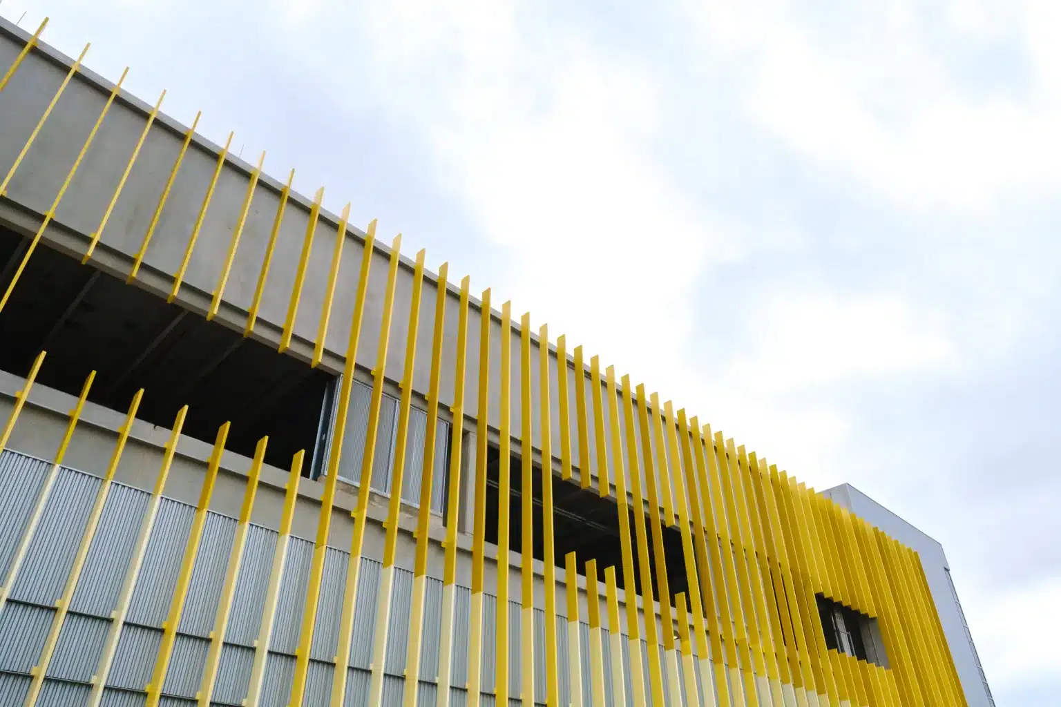 Gold vertical fins over metal panels on the facade of the Palmer warehouse against a cloudy sky