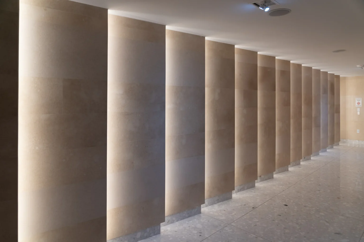 Corridor lined with backlit stone-clad pilasters at Flamingo Point in Miami Beach