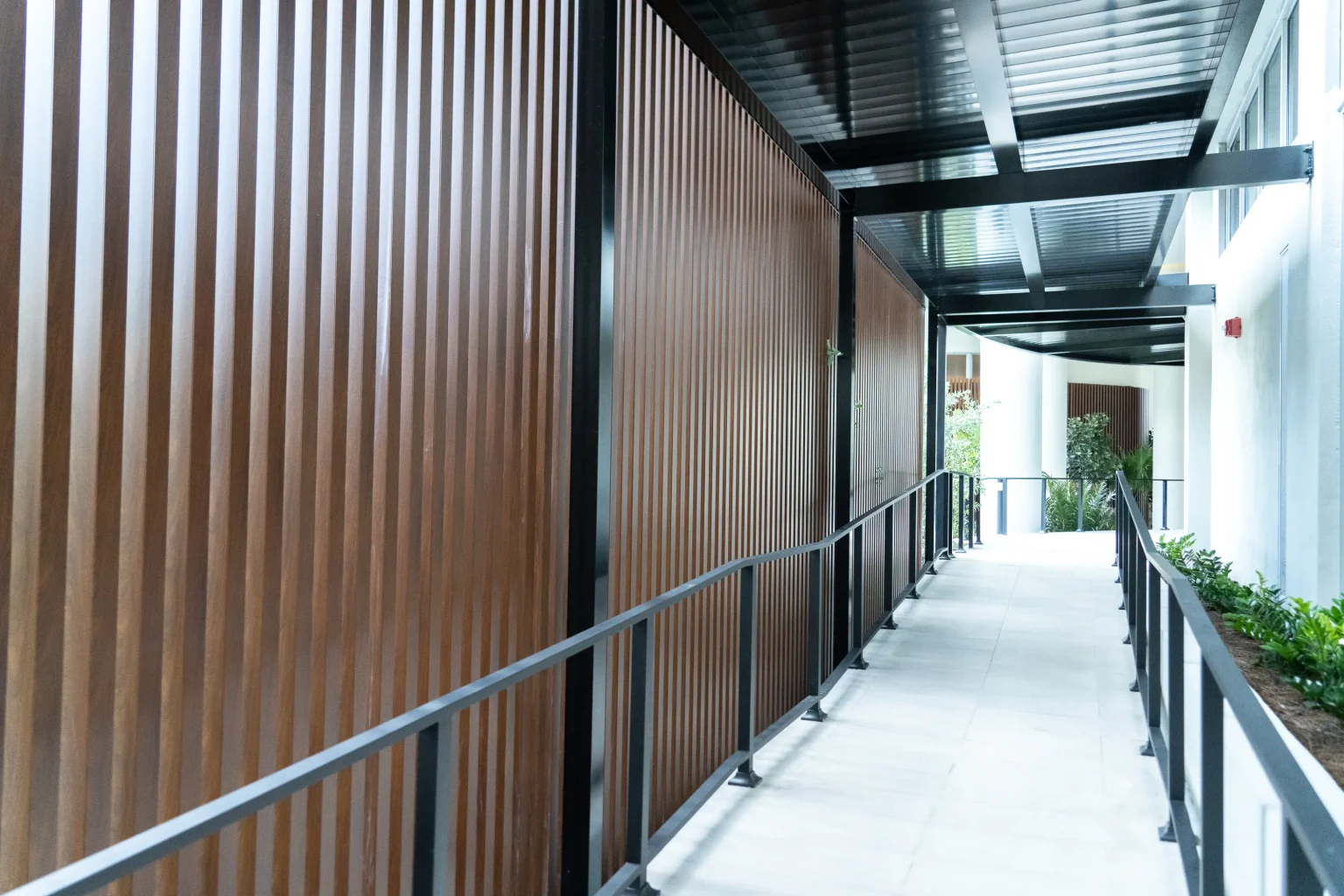 Covered walkway with dark wood slat screens and metal railings at Flamingo Point in Miami Beach