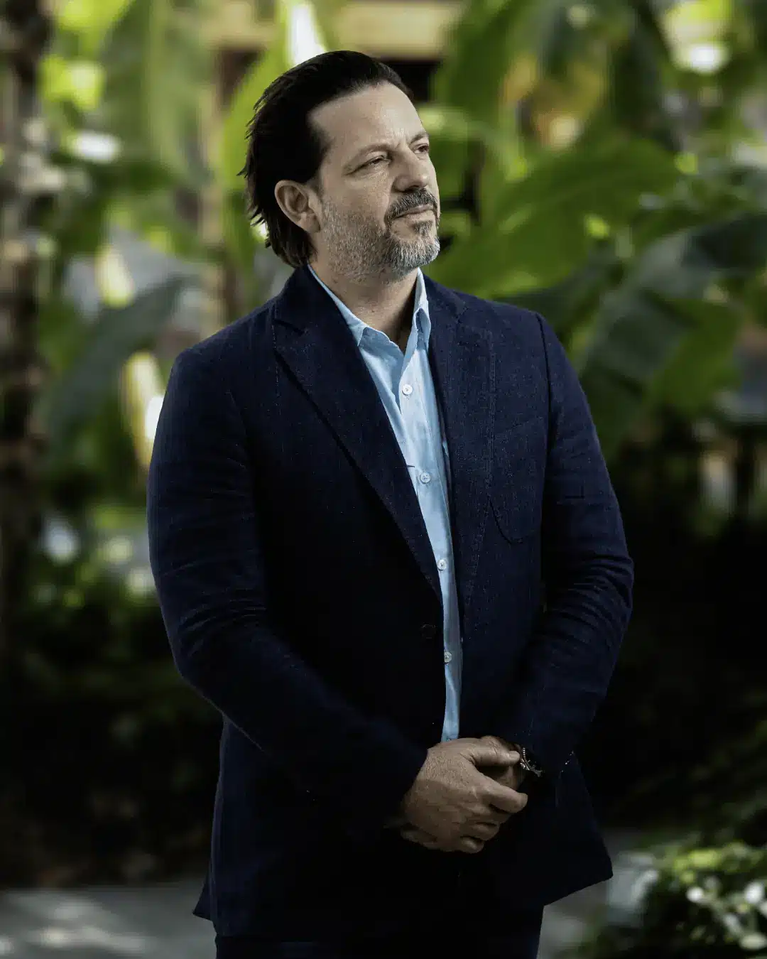 Executive portrait of a man in a navy blazer and light blue shirt among tropical greenery