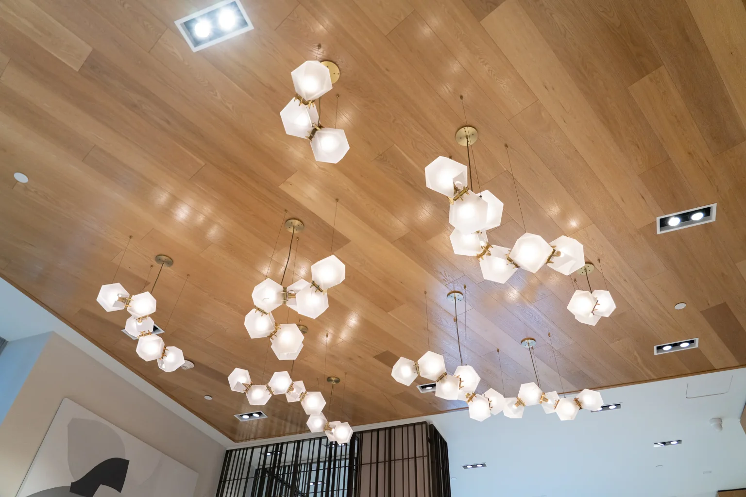 Sculptural glass chandeliers hanging from a wood plank ceiling in the lobby of Flamingo Point in Miami Beach