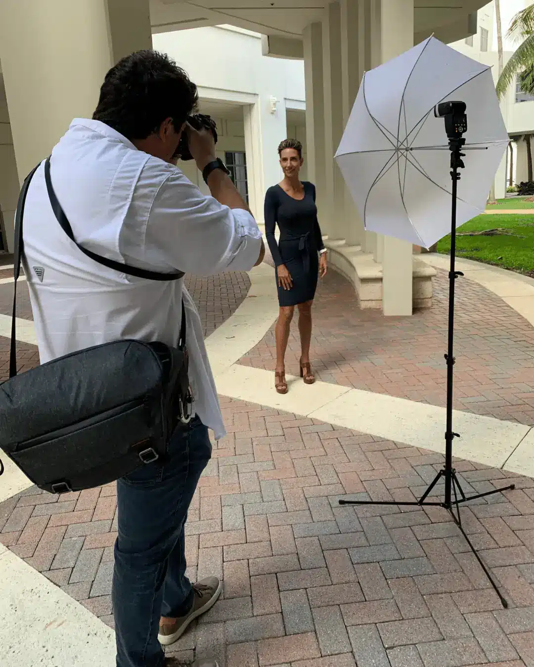 Drone Permission photographer with an umbrella light taking an outdoor corporate headshot of a woman in a navy dress